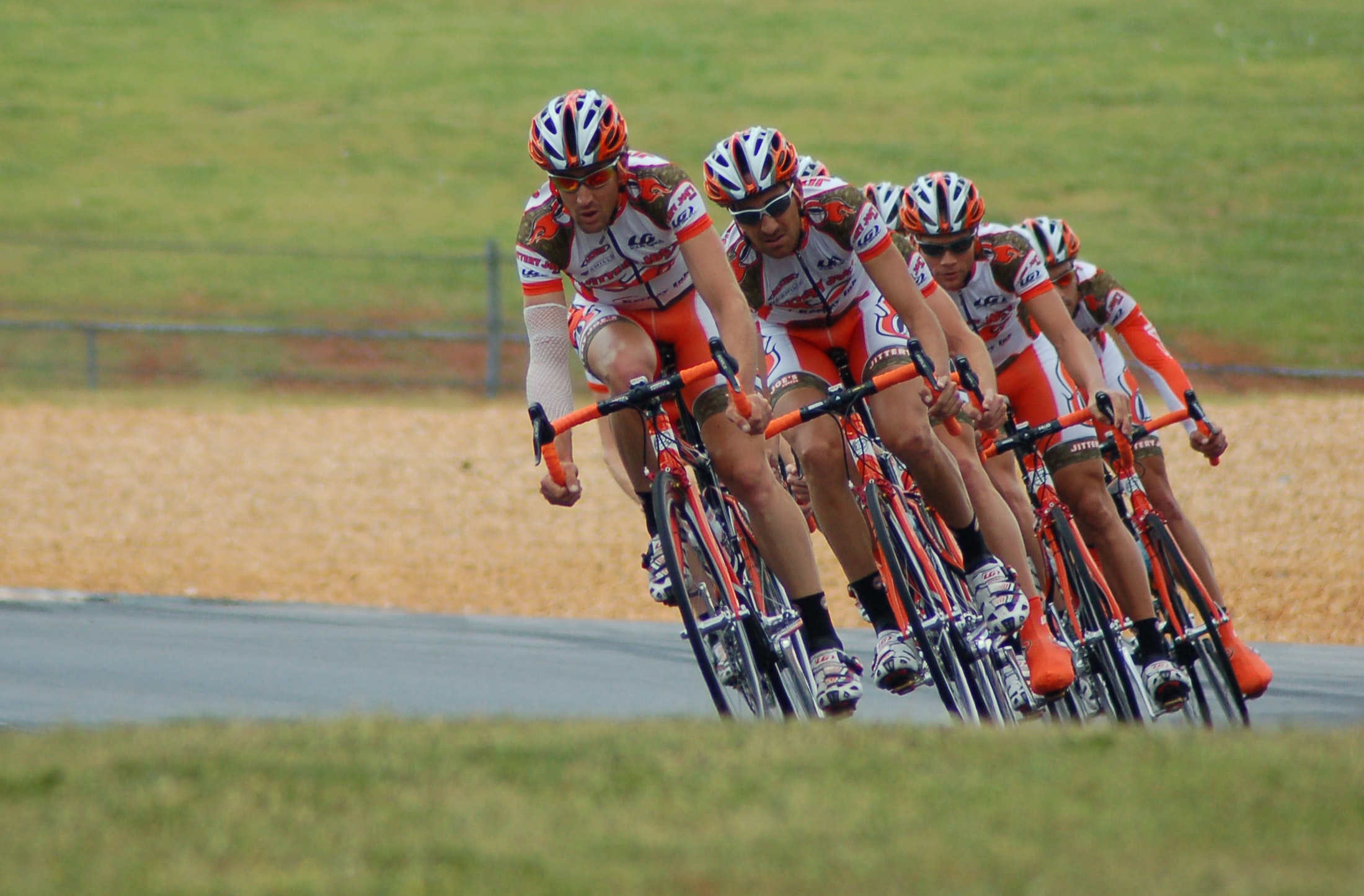 A group of cyclists in professional attire engage in a road race