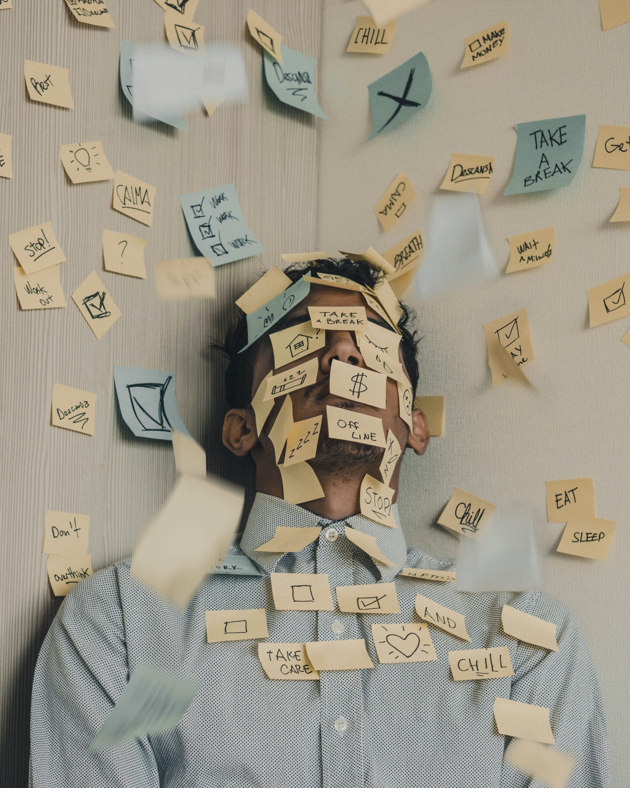 A man covered in and surrounded by dozens of sticky notes, each with a different to-do item
