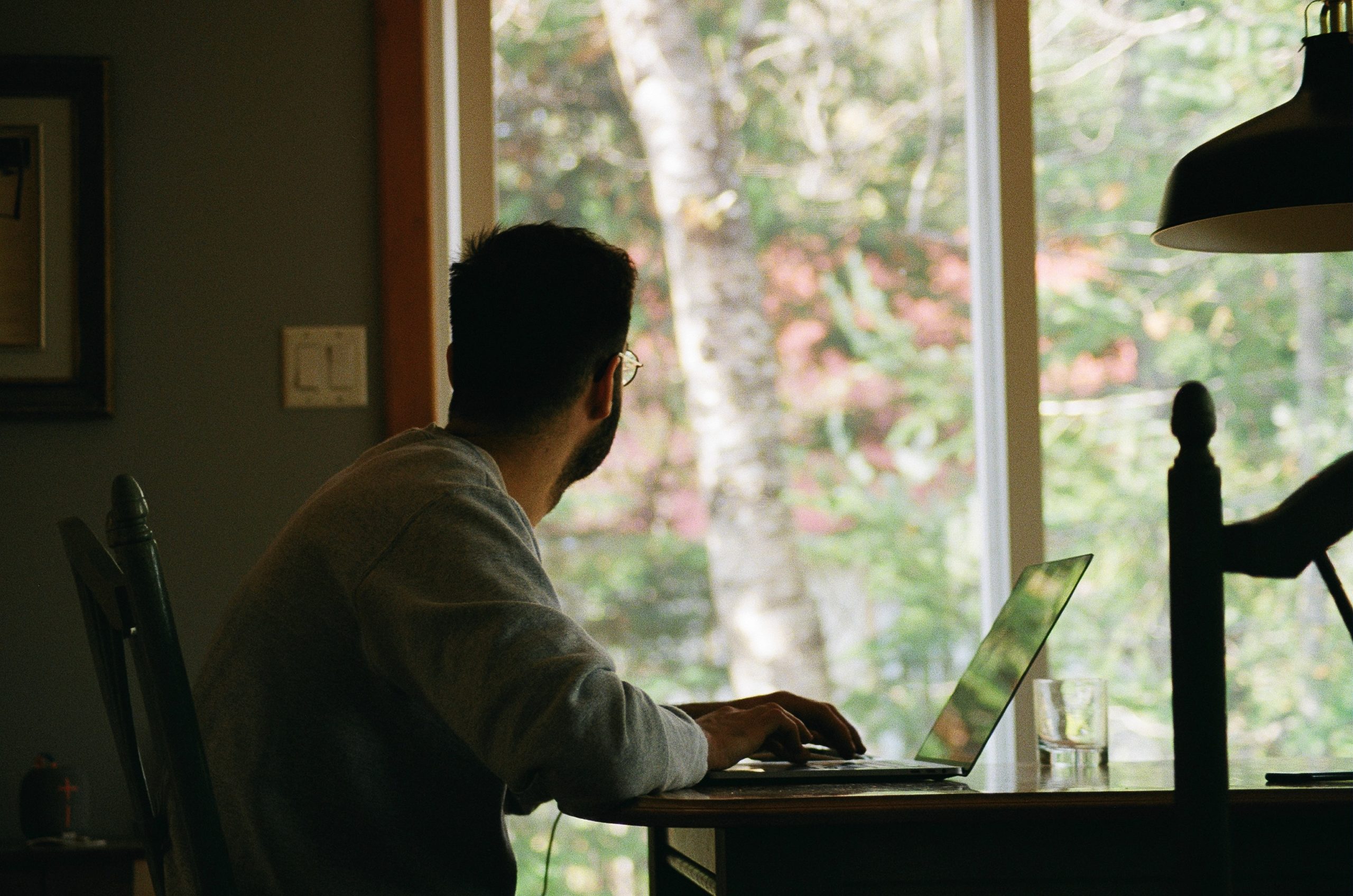 Man in a home office setup looking out the window