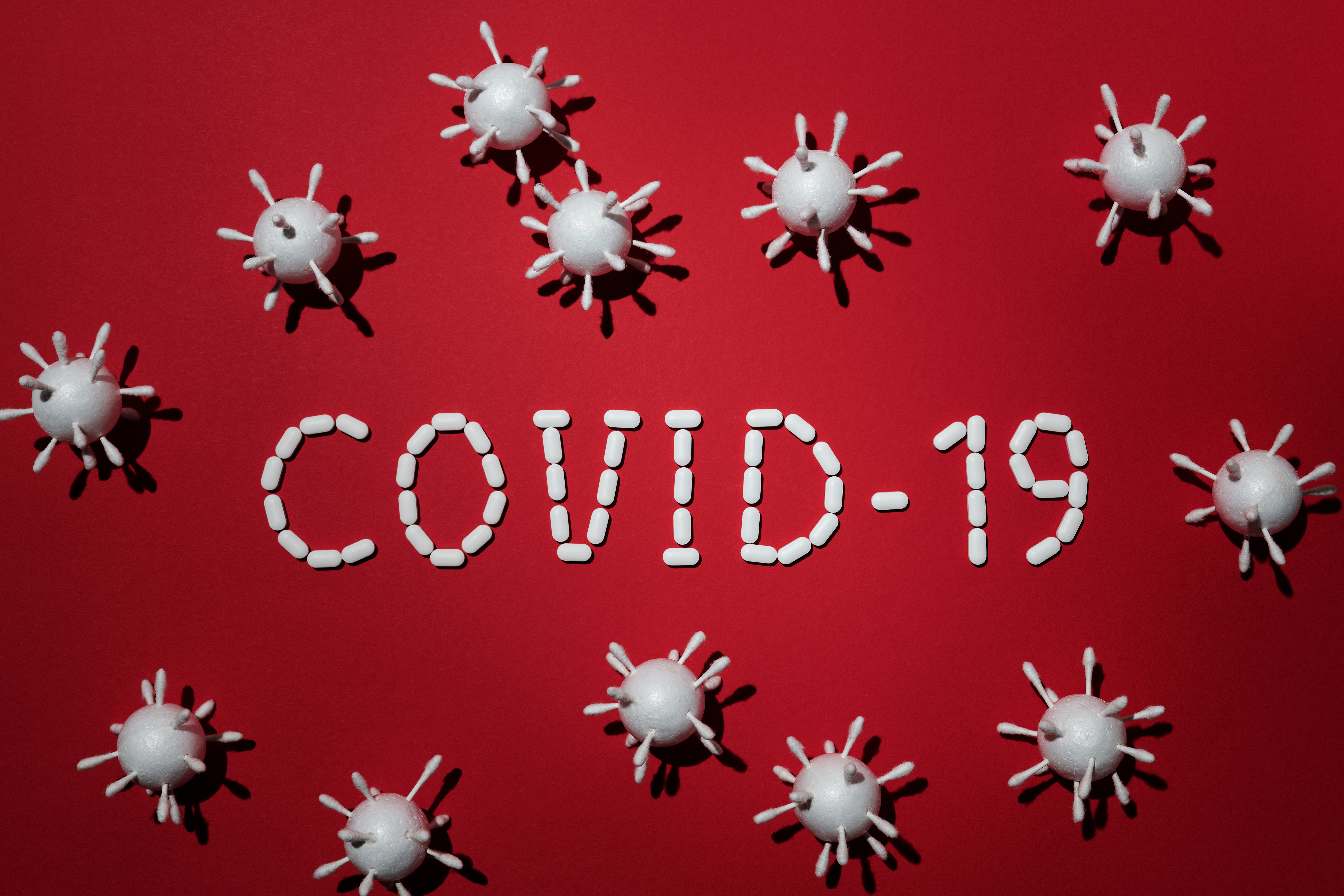 A red banner with COVID-19 text and molecular structural models of the virus in white.