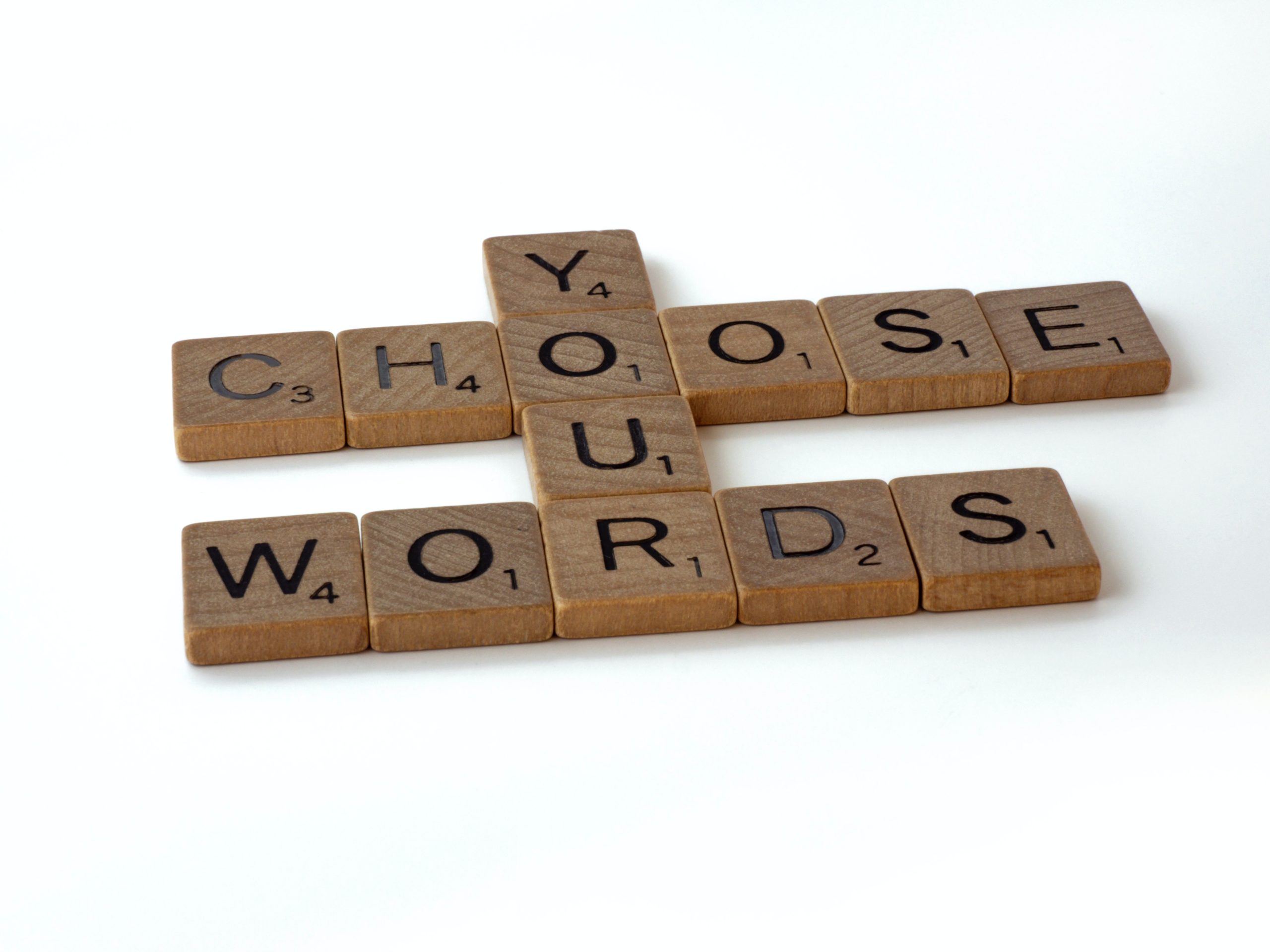 “Choose your words” spelled out in wooden tiles arranged on a table
