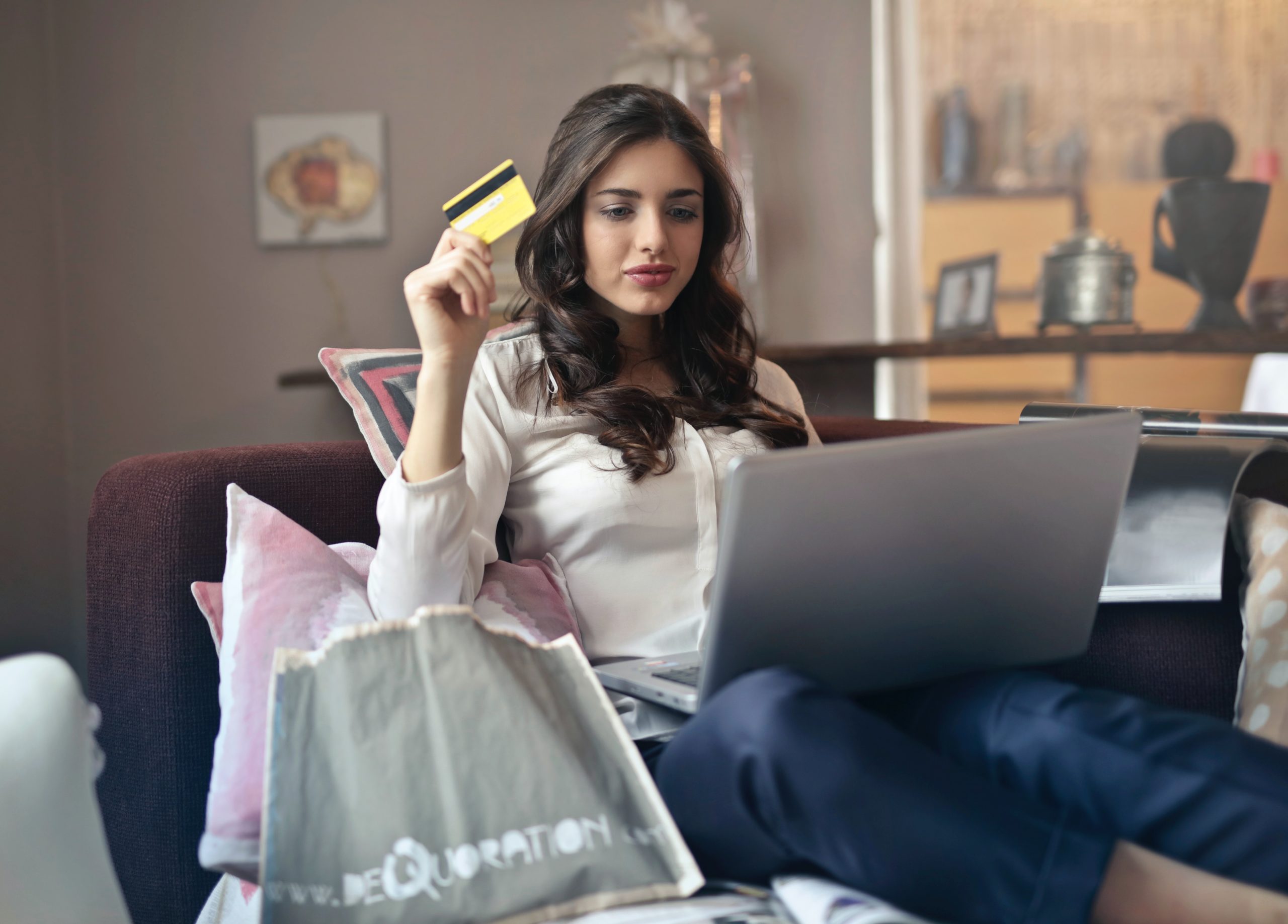 A woman holding her credit card and using her laptop.
