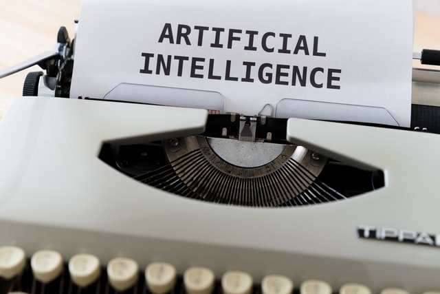 A black and white typewriter with the words “artificial intelligence” typed on the page.