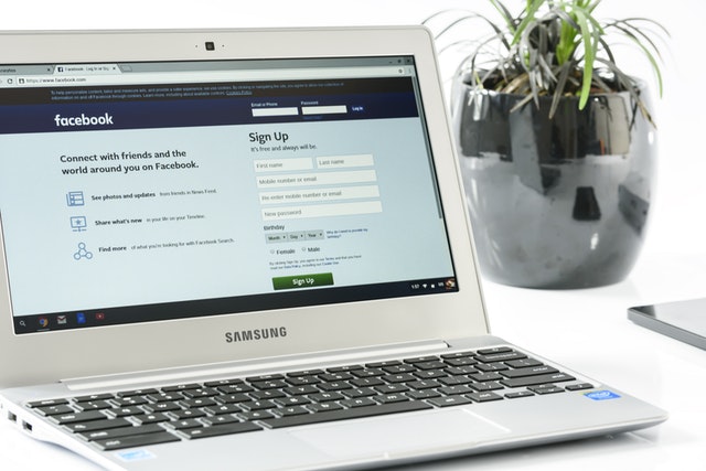 A laptop placed on a table with its screen displaying the Facebook login page.