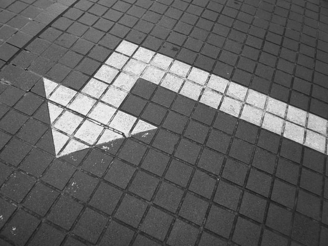 A white arrow on bricked pavement.