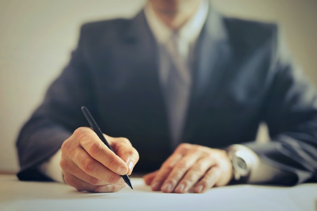 A businessman holding a pen to sign a document