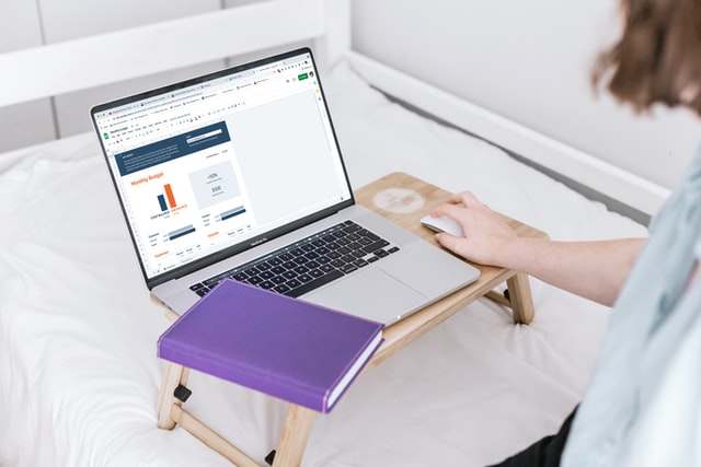 Laptop, diary and woman holding a laptop mouse on portable laptop stand