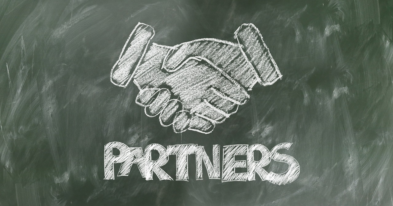 Blackboard drawing of a handshake with the word “partners” spelled below.