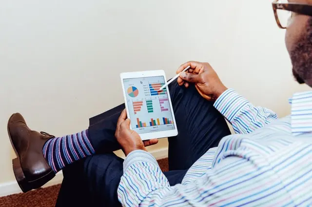 A man in business attire looks at market analytics on his device.
