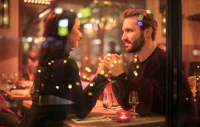 A couple holding hands over glasses of Champagne in a restaurant.