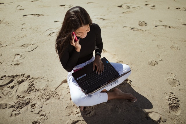 Woman working while sitting on sand