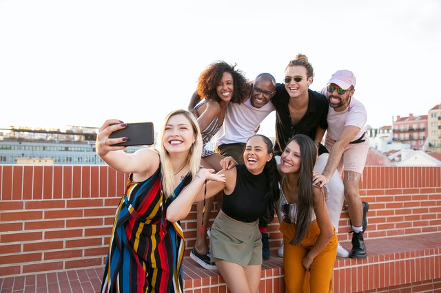 A group of young men and women taking a selfie on a rooftop.
