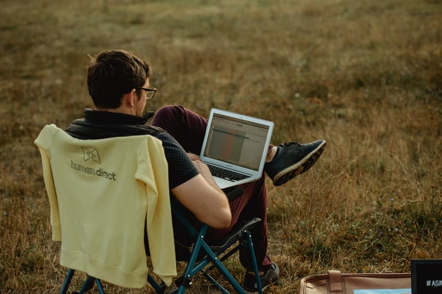 A man sitting on a camping chair with a laptop