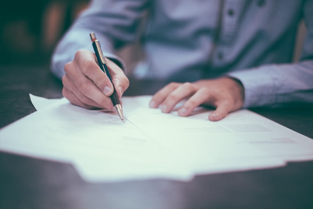 Image representing a person signing bank papers for a loan.