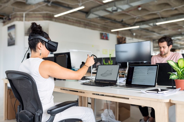 Woman using laptop with virtual reality headset