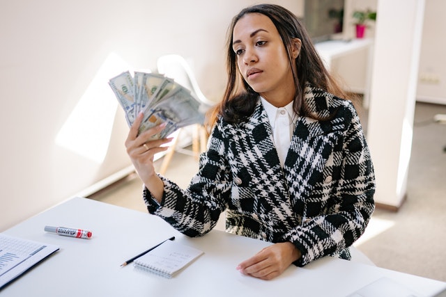 A woman in a plaid coat holding money