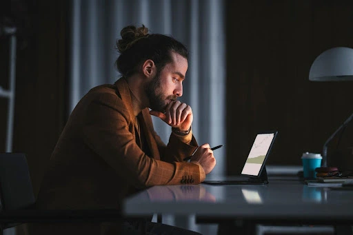 A pensive man looks at his computer screen.