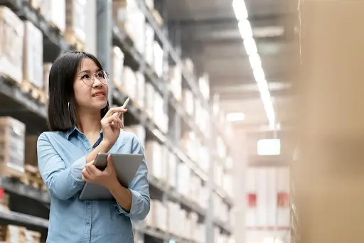 Woman uses a smart tablet to take inventory in a warehouse.