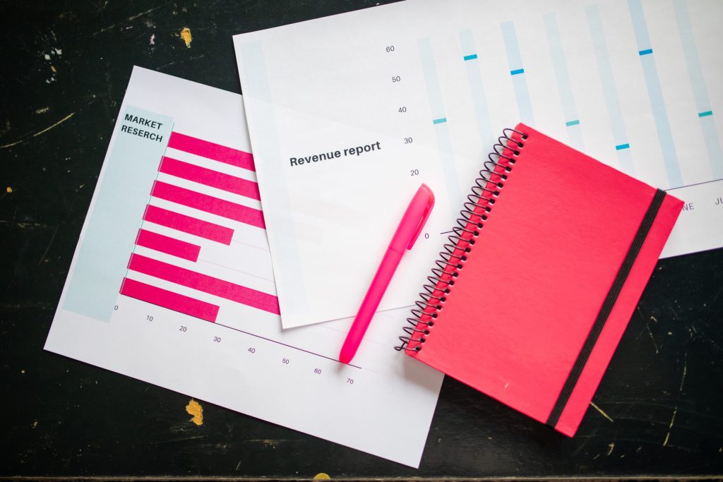 Overhead shot of a pen and notebook placed on a business’s financial charts.