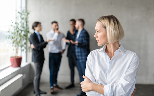 Woman cringes as work colleagues gossip.