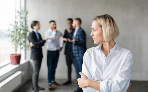 Woman cringes as work colleagues gossip.